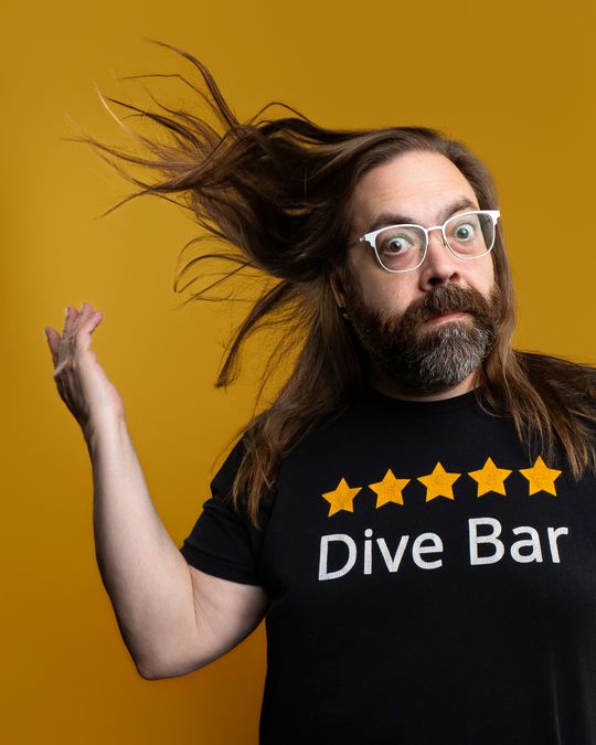 Gabriel Rutledge flipping his hair, wide-eyed, against a gold backdrop